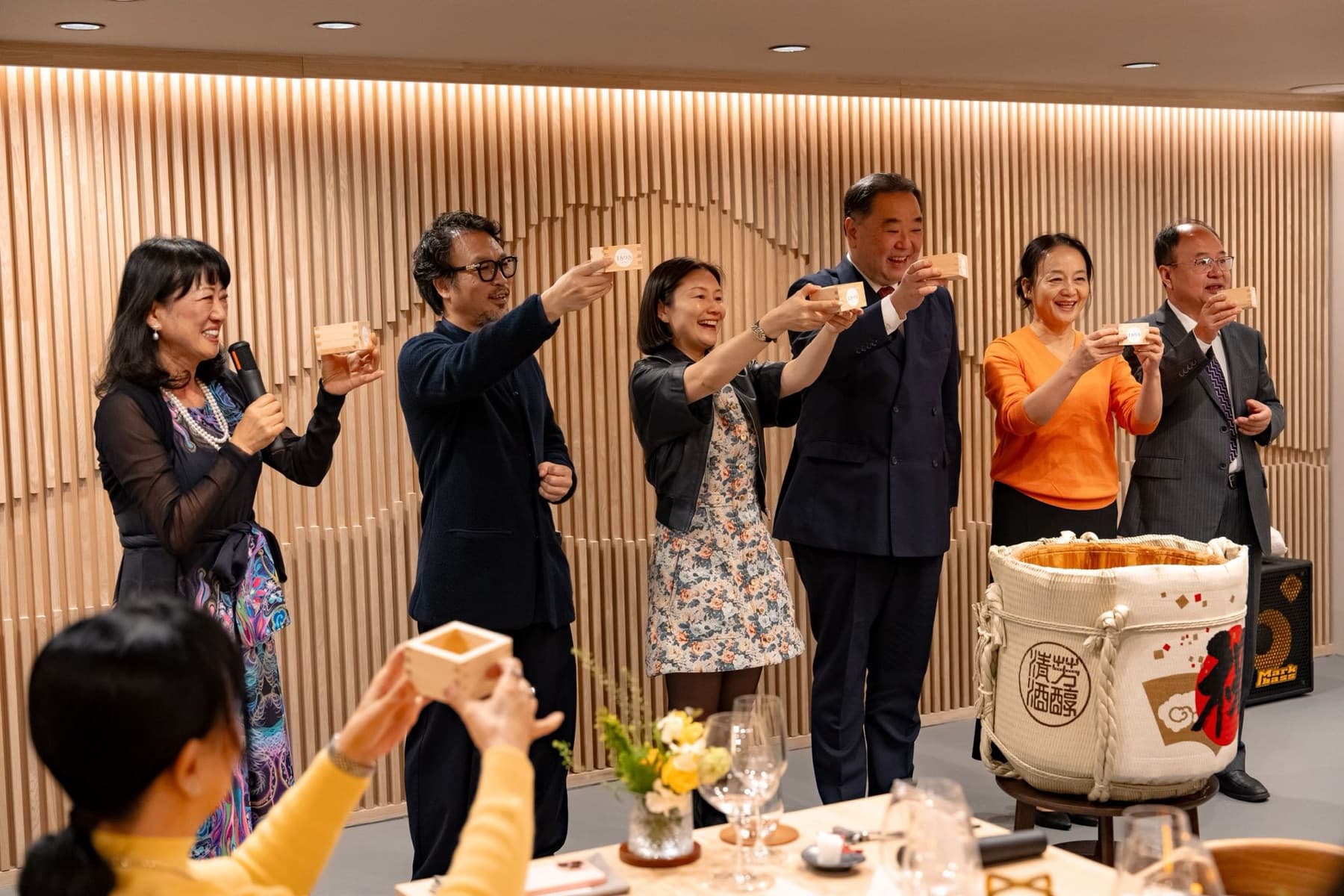 Opening kanpai — guests raise sake masu cups bearing the 1898 mark