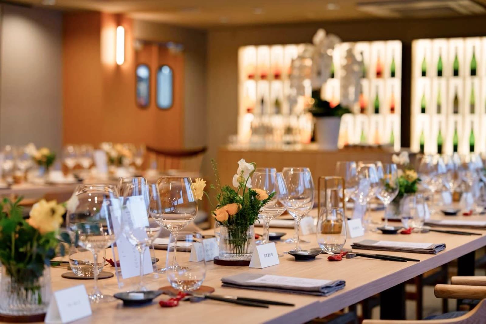 Cantonese restaurant — long table set with sake bottles backlit, late evening