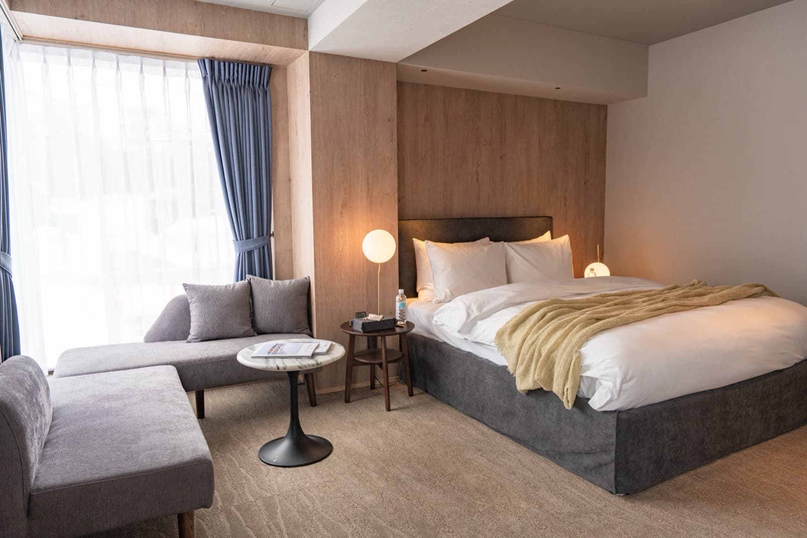Suite — charcoal-linen bed, sitting area, soft lamp light